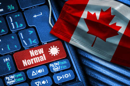 Concept of New Normal in Canada during Covid-19 with computer keyboard red button text and face mask showing Canadian Flag.の写真素材