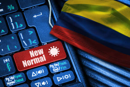 Concept of New Normal in Colombia during Covid-19 with computer keyboard red button text and face mask showing Colombian Flag.の写真素材