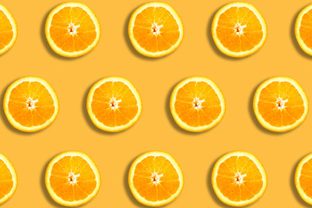Fruit pattern with sliced oranges on orange background. Top view. Summer concept.の写真素材