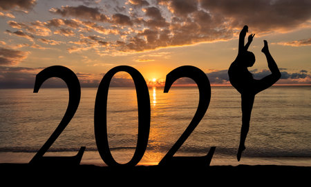New Year 2021 sunrise by the beach with silhouette of woman in dance pose.の写真素材