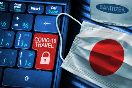 Japan COVID-19 coronavirus travel restrictions concept showing red button warning on keyboard with Japanese flag face mask and hand sanitizer. New normal in global travel.の写真素材