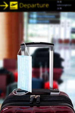 Travel suitcase and medical mask at defocused airportの写真素材