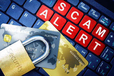Scam Alert in red keys on high-tech computer keyboard background with security engraved lock on fake credit cards. Concept of Internet security, data privacy, cybercrime prevention for online shopping transaction payments.の写真素材