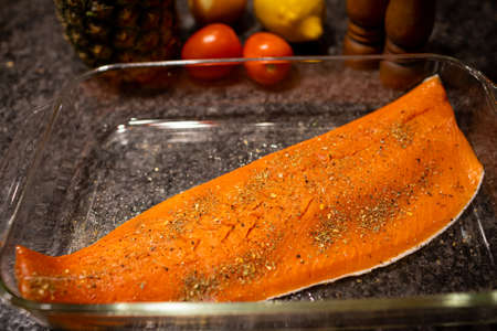 Raw wild caught salmon fish fillet seasoned and ready to bake in baking dish.の写真素材