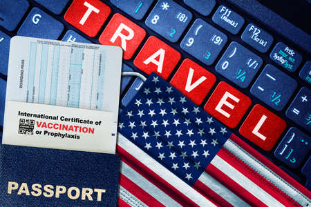 US new normal travel concept with passport, boarding pass, face mask with US flag and certificate of  vaccination on keyboard. Vaccine passport concept.の写真素材