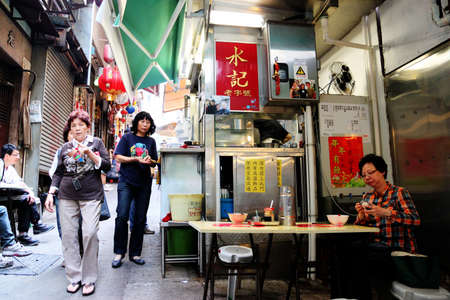 HONG KONG - APR. 19, 2011: Lunch time crowd eat at open-air street food stalls known as Dai Pai Dong in Hong Kong Central. These outdoor kitchens are now a Hong Kong heritage and culture.のeditorial素材