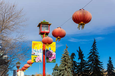 Calgary, Canada - November 13, 2021: Red lanterns hang on Chinese street lamps with colorful banners in downtown Chinatown in Calgary.のeditorial素材