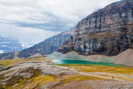 Hikers on the trail beside Pinnacle Mountain and Minnestimma Lakes at Sentinel Pass near Lake Louise in Banff National Park, Alberta, with heavy clouds descending on Larch Valley.の写真素材