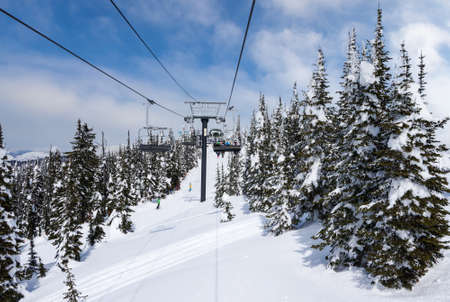 Ski chairlift going up a ski slope in the snowy mountain range of Big Mountain in Whitefish, Montana, at Glacier National Park, USA.の写真素材