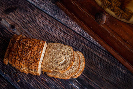 Freshly baked whole wheat flax and sunflower seed bread sliced on rustic wooden table with bread box and copy space.の写真素材