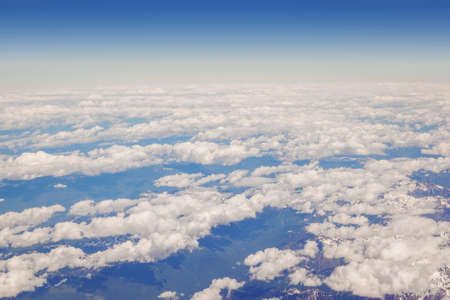 Fluffy clouds and blue sky from above the clouds, viewed from an airplane.の写真素材