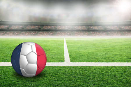 Football in brightly lit outdoor stadium with painted France flag. Focus on foreground and soccer ball with shallow depth of field on background and copy space.の写真素材
