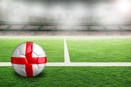 Football in brightly lit outdoor stadium with painted England flag. Focus on foreground and soccer ball with shallow depth of field on background and copy space.の写真素材