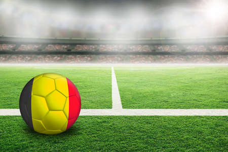 Football in brightly lit outdoor stadium with painted flag of Belgium. Focus on foreground and soccer ball with shallow depth of field on background and copy space.の写真素材