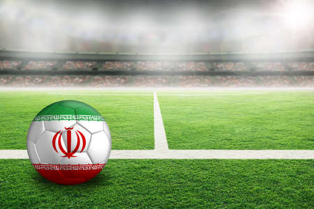 Football in brightly lit outdoor stadium with painted flag of Iran. Focus on foreground and soccer ball with shallow depth of field on background and copy space.の写真素材