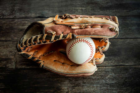 Leather baseball or softball glove with ball on rustic wooden background.の写真素材