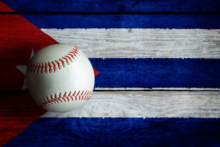 Leather baseball on rustic wooden background painted with Cuban flag with copy space. Cuba is one of the top baseball nations in the world.の写真素材