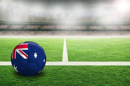 Australia football in brightly lit outdoor stadium with painted Australian flag. Focus on foreground and soccer ball with shallow depth of field on background and copy space.の写真素材