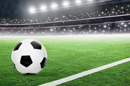 Football in brightly lit fictitious outdoor stadium with spectators and camera flashes. Focus on foreground soccer ball with shallow depth of field on background and copy space.の写真素材