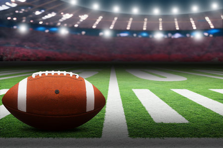 American football on field in stadium with dramatic spot lighting and copy space. Focus on foreground ball with shallow depth of field on background.の写真素材