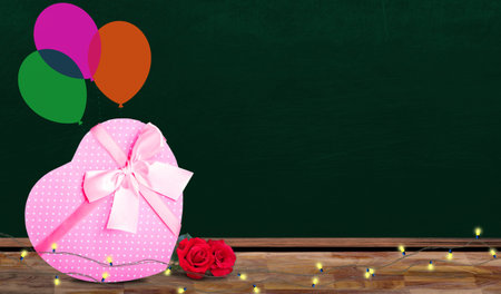 Happy Valentine's Day banner with chalkboard copy space surrounded by pink gift box, balloons, roses and string lights.の写真素材
