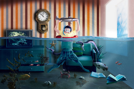 Creative boy making the most of his flooded home by catching a fish and enjoying his imaginative adventure while home alone.の写真素材