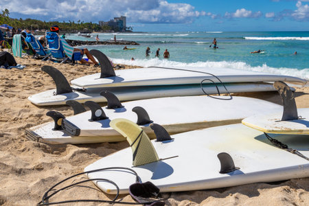 Surfboards showing fins and leash ankle straps lying on the sand at Waikiki beach in Honolulu...