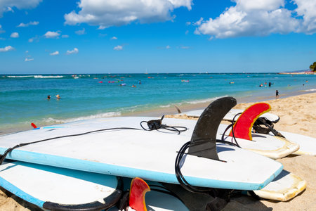 Surfboards showing fins and leash ankle straps lying on the sand at Waikiki beach in Honolulu Hawaii. Defocused background.の写真素材