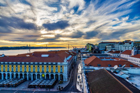 Sunset view from atop Rua Augusta Arch showing Commerce Square and Rua do Arsenal Street toward Belem in Lisbon, Portugal, with April 25 Bridge across the Tagus River in the background.の写真素材