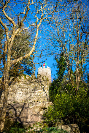 Flag of Portugal on top of the Moorish Castle or Castelo dos Mouros in Sintra, as seen through the woods.  It was a fortification built in the 10th century when the Moors occupied the Iberian Peninsula.の写真素材