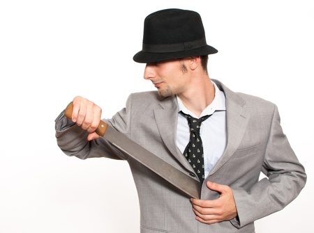 Handsome young caucasian businessman pulling out a machete from his suitの写真素材