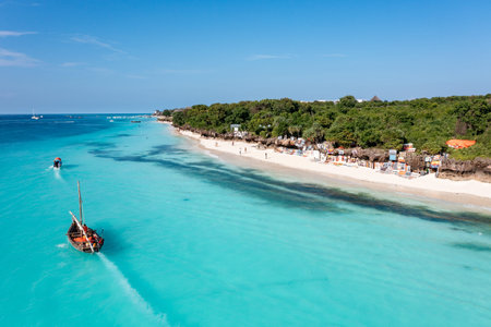 Zanzibar beach scene with dhow boats and tourists enjoying the turquoise water