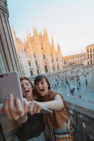 Two friends take a selfie in front of the Duomo di Milanoの写真素材