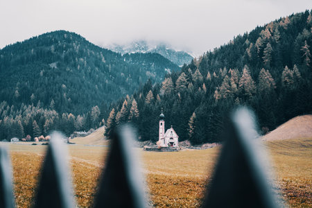St Johann church in Ranui Funes valley, Dolomites, Italy, surrounded by autumn treesの写真素材