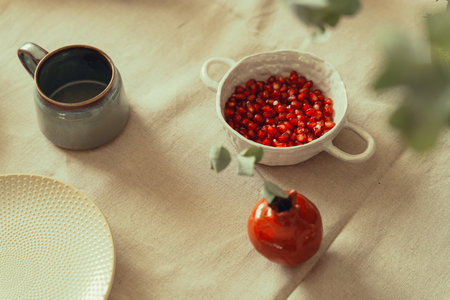 Autumn table setting with fresh pomegranate seeds, mug, and plate for a healthy snack.の写真素材