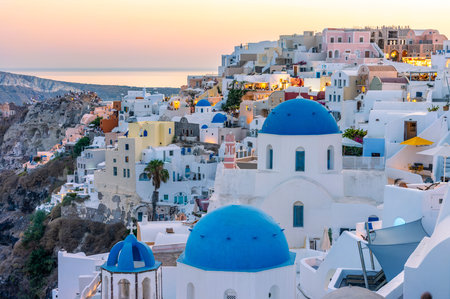 Oia Santorini sunset. People admire iconic blue domed churches and caldera views