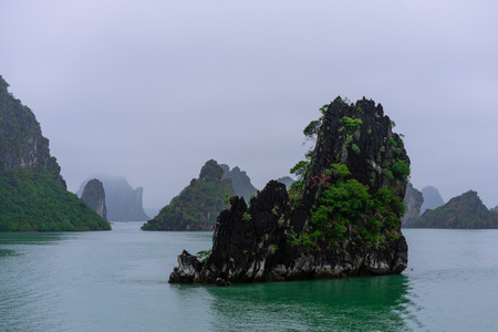 Mystical atmoshpere in the world famous halong bay. the limestone green rocks and the emerald green water gave a great contrast to the cloudy scene.の写真素材