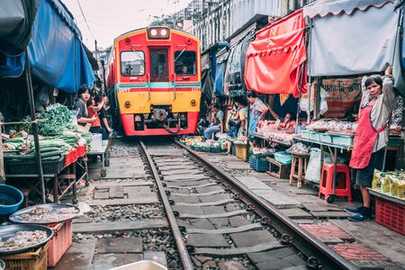 maeklong railway market 12.13.2018 Tourists visit the railway market outside bangkok and buy goods from the vendorsのeditorial素材