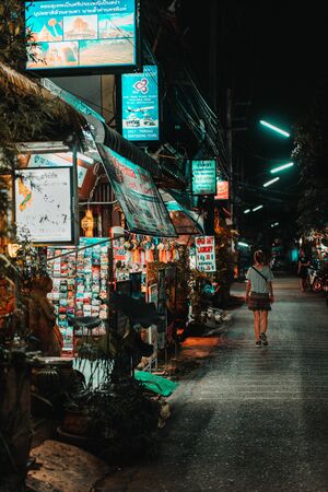 Chiang Mai, Thailand, 12.16.18: Hipster girl walking alone in the streets. Some businesses are still open and lightens up the streetのeditorial素材