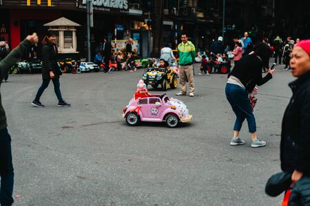 Hanoi, Vietnam, 12.20.18: Life in the street in Hanoi. One of the main roads is closed down at the weekend and opens to the public to have some fun on the street. Little girl drives in a plastic car.のeditorial素材