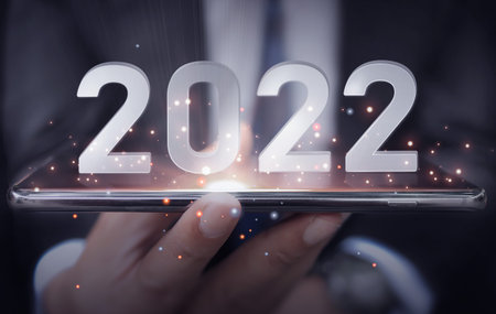 Close-up, A man holding Mobile and numbers 2022 is a startup concept driving global business in the...
