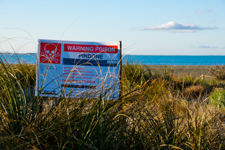Warning poison signboard at the sea side with blue skyの写真素材