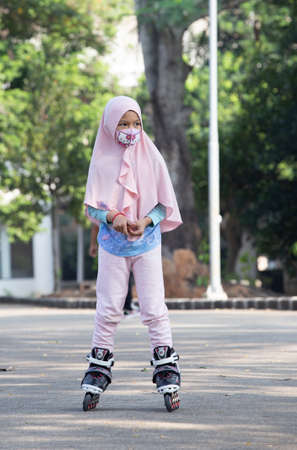 cute asian muslim girl wearing face mask and roller skatesの写真素材