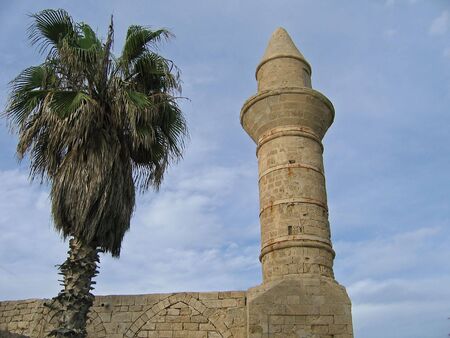 Details of an old mosque tower with palm tree next to itの写真素材