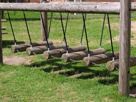 Wooden children swings in a playground park outdoorsの写真素材