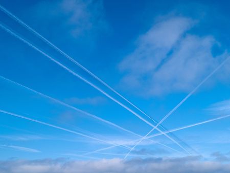 Aerial crossroad clear blue sky with crossing jets contrails trafficの写真素材