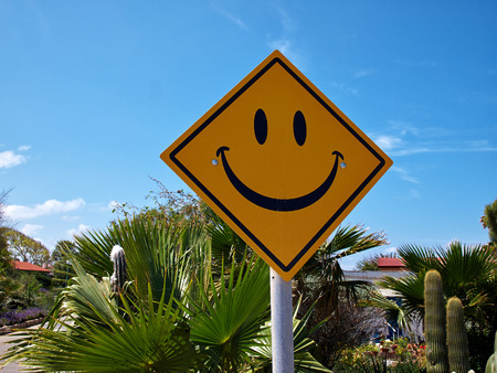 Conceptual funny road sign with a smiley face with clear blue sky backgroundの写真素材
