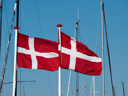 Flag of Denmark up high in the air with clear blue sky backgroundの写真素材