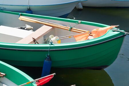 Green small fishing boat dinghy with equipment in a port marinaの写真素材