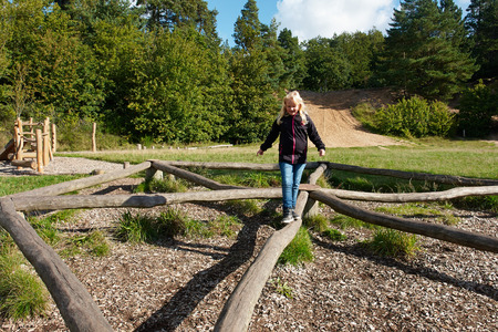 Young cute girl play in a creative playground made of wood in the middle of natureの写真素材